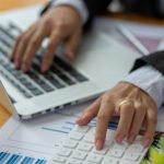 Close up of Business using calculator and laptop for do math finance on wooden desk, tax, accounting, statistics and analytical research concept